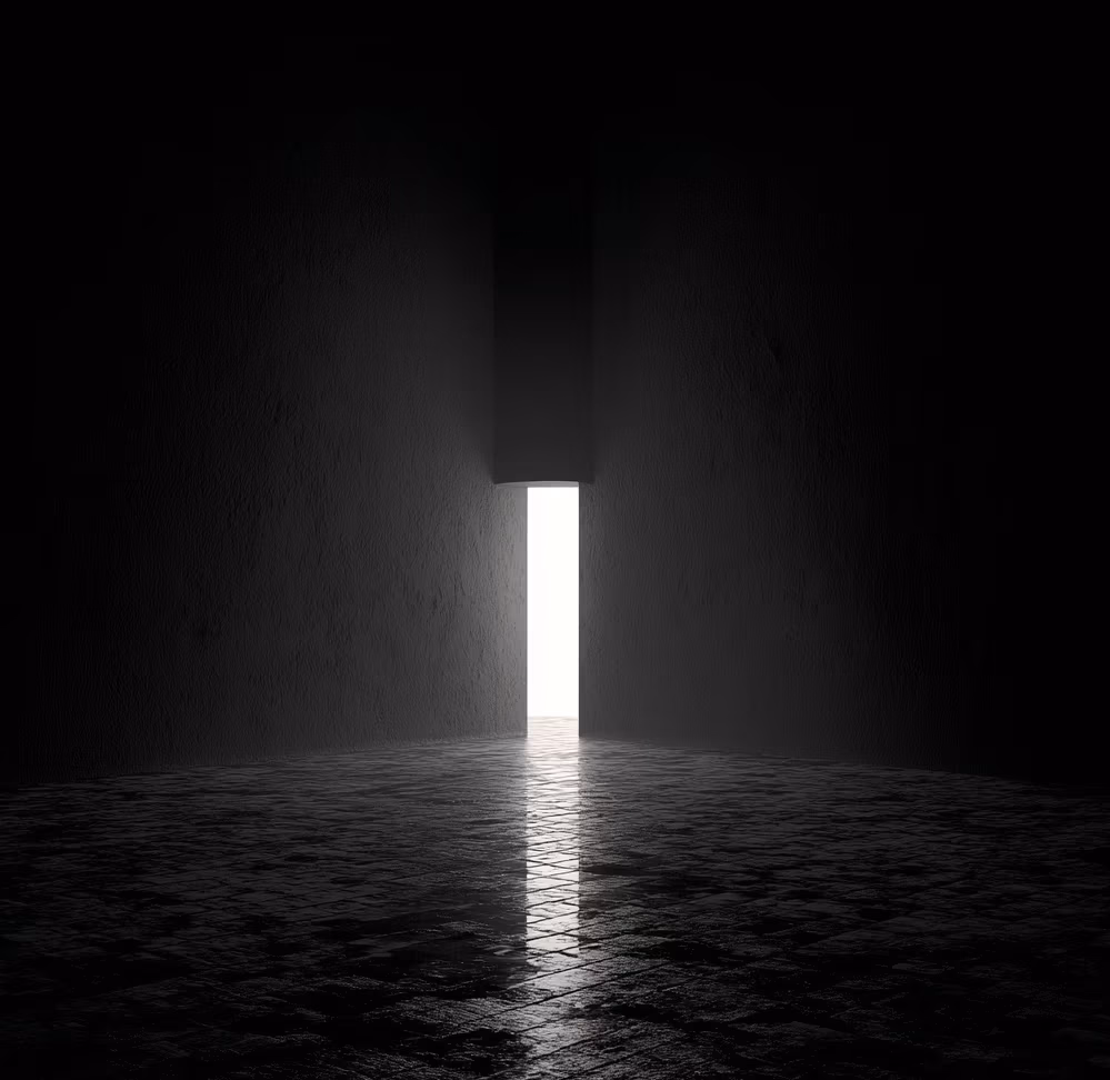 In the darkness, there is a glowing door in the middle of the picture